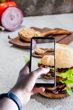 Hamburgerin fotoğrafını çeken akıllı telefonları kaldıran eller. Mesaj için yer var. Seçici odak