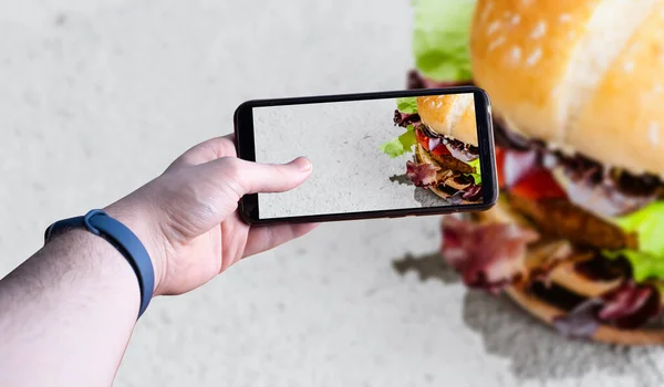 Hamburgerin fotoğrafını çeken akıllı telefonları kaldıran eller. Mesaj için yer var. Seçici odak