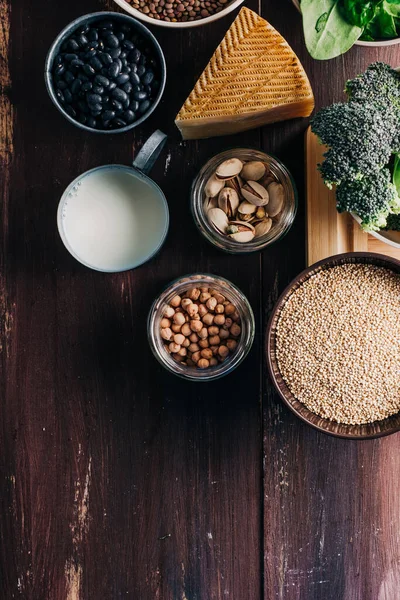 Vejetaryen ve vejetaryen proteinleri, ahşap masada doğal ürünler. Nohut, fasulye, brokoli, kinoa, ıspanak, şam fıstığı vs. Hayvan proteini yerine