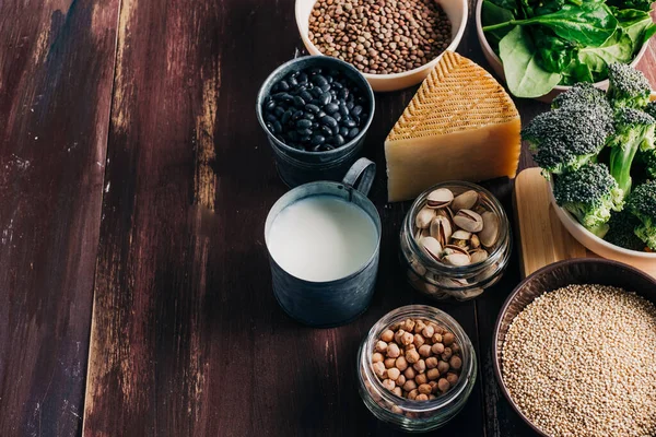 Vejetaryen ve vejetaryen proteinleri, ahşap masada doğal ürünler. Nohut, fasulye, brokoli, kinoa, ıspanak, şam fıstığı vs. Hayvan proteini yerine