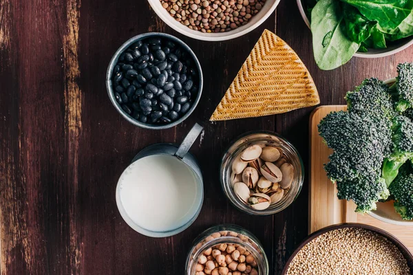 Vejetaryen ve vejetaryen proteinleri, ahşap masada doğal ürünler. Nohut, fasulye, brokoli, kinoa, ıspanak, şam fıstığı vs. Hayvan proteini yerine