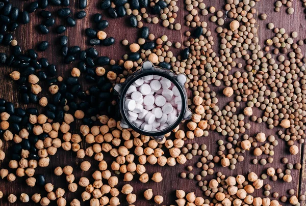 baklagiller vitaminler, ahşap masada vitamin hapları nohut, mercimek ve fasulye.