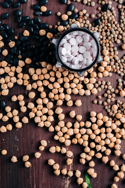 baklagiller vitaminler, ahşap masada vitamin hapları nohut, mercimek ve fasulye.