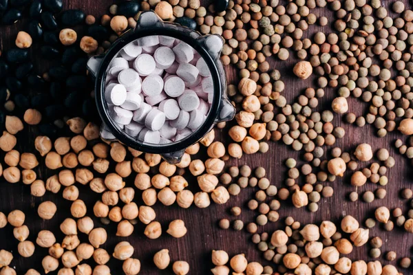 baklagiller vitaminler, ahşap masada vitamin hapları nohut, mercimek ve fasulye.