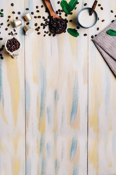 Kahve çekirdekleri, hafif ahşap masa, kahve kapsülü ve bir fincan kahve. Üst Manzara. Kopyalama alanı.