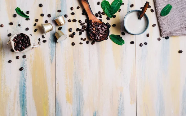 Kahve çekirdekleri, hafif ahşap masa, kahve kapsülü ve bir fincan kahve. Üst Manzara. Kopyalama alanı.