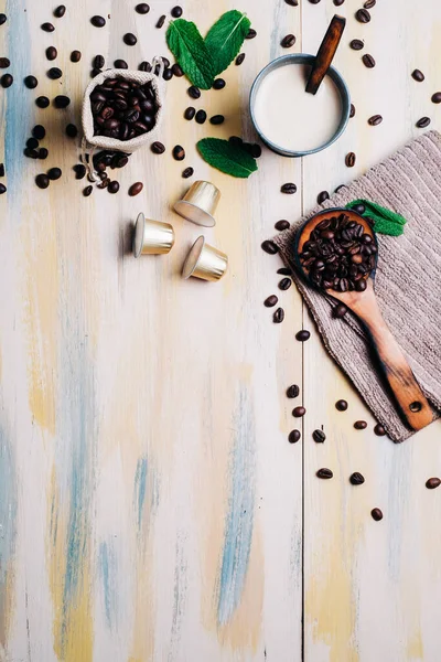 Kahve çekirdekleri, hafif ahşap masa, kahve kapsülü ve bir fincan kahve. Üst Manzara. Kopyalama alanı.