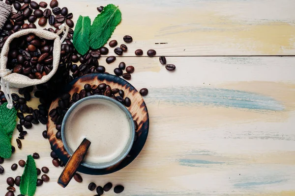 Eski ahşap masada kahve fincanı ve dağınık kahve çekirdeği. Üst Manzara. Mesaj için yer var. Kopyalama alanı
