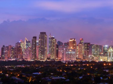 Makati, Metro Manila, Filipinler - Ocak 2016: Makati ve şehir ışıklarının akşam üstü gökyüzü. Önde zengin, alçak katlı bir apartman var..