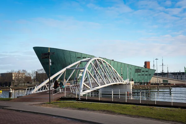 Amsterdam, nordholland / niederland-dezember 3.12.2016: grüner bau des nemo science museum und weiße brücke, die dorthin führt. Dieses Museum ist das am fünftmeisten besuchte Museum in den Niederlanden. — Stockfoto