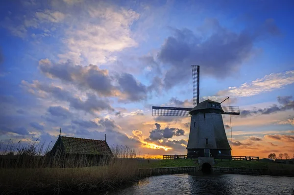 Watermolen naast een kanaal van de Eilandspolder in zonsondergang, Nederland — Stockfoto