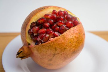 Olgun narı beyaz bir tabakta aç, üzerinde taneler olsun.