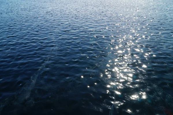 Deep blue ice sparkling like water ripples and a Sunny path on it