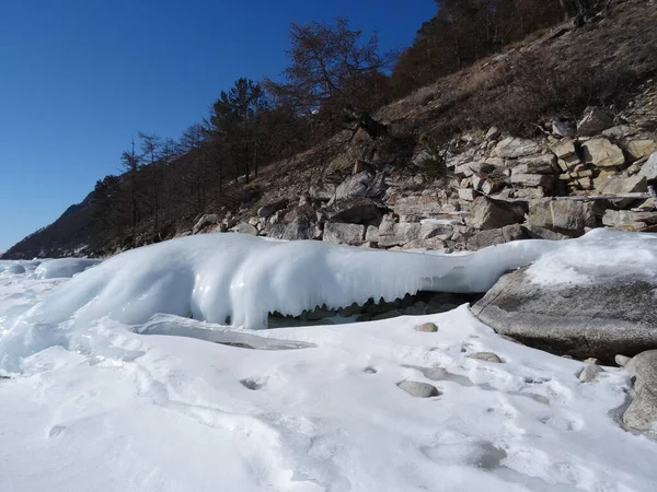 真っ青な空に向かって岩の海岸で凍る青い波と白い波 — ストック写真