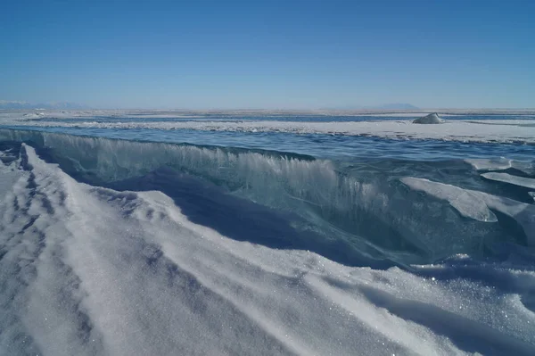 湖の氷で覆われたビュー 青い空に対して氷の輝く滑らかな表面の深い亀裂 — ストック写真