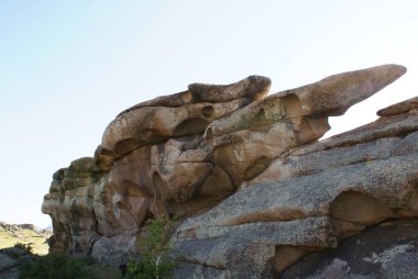 Mavi gökyüzüne karşı bir testere balığının burnuna benzeyen alışılmadık şekilli bir kaya. Disnceta 'da dağlar görülebilir.