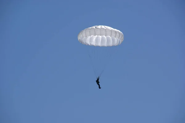 skydiver in the blue sky on a white parachute