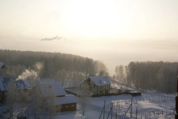 Top view of cottages, forest and fog in winter