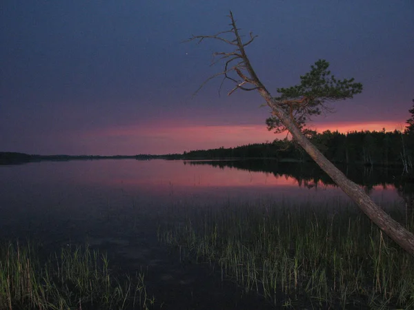 night view of the dark lake and the sky painted in the maroon colors of the sunset
