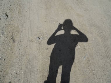 Toprak bir yolda bir fotoğrafçının gölgesinde