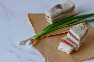 Sarımsaklı salo ve kağıt üzerinde yeşil soğan.