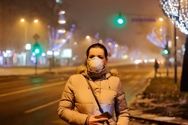Onu virüslerden, dumandan, egzoz dumanından ve yoğun sisteki diğer atmosferik kirleticilerden korumak için maske takan genç bir kadın. Sağlık, ekoloji ve hava kirliliği hakkında kavramsal fotoğraf.
