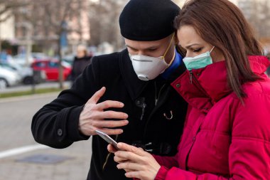 Maske takan genç bir çift, onları büyük şehirlerdeki virüslerden, dumandan ve diğer atmosferik kirleticilerden korumak için. Sağlık, ekoloji ve hava kirliliği hakkında kavramsal fotoğraf.