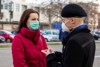 Maske takan genç bir çift, onları büyük şehirlerdeki virüslerden, dumandan ve diğer atmosferik kirleticilerden korumak için. Sağlık, ekoloji ve hava kirliliği hakkında kavramsal fotoğraf. Seçici odak.