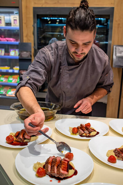 Chef arranging dry aged rib eye steak roast on creamy mashed celery with red wine reduction sauce before serving it to guests. Selective focus. Restaurant and fine dining concept.
