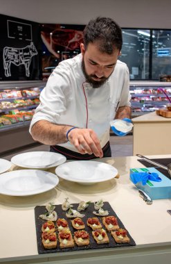 Şef servis etmeden önce siyah lav tabağındaki aperatifleri tatlandırıyor. Eğlence marketi. Seçici odaklanma. Restoranlar ve güzel yemek konsepti..