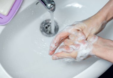 Banyoda musluğun altında ellerini sabunla yıkayan bir kadın. Kapsamlı tıbbi prosedür için adım adım resim talimatları. Yedinci adım, sağ başparmağı yıka..