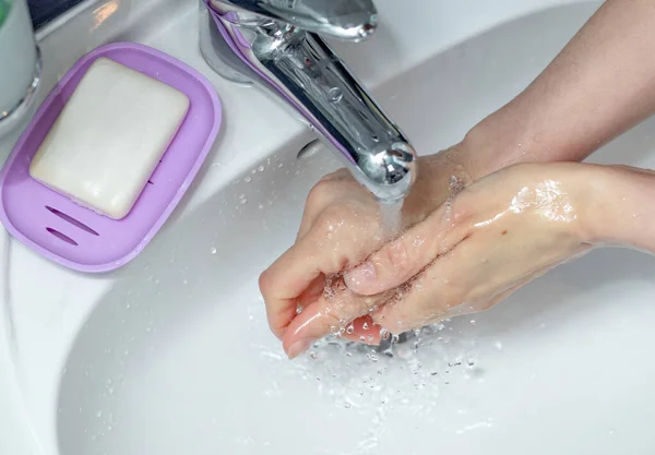 Woman washing hands with soap under the faucet in bathroom. Step by step picture instructions for thorough medical procedure. Step 8, rinse your hands in water.