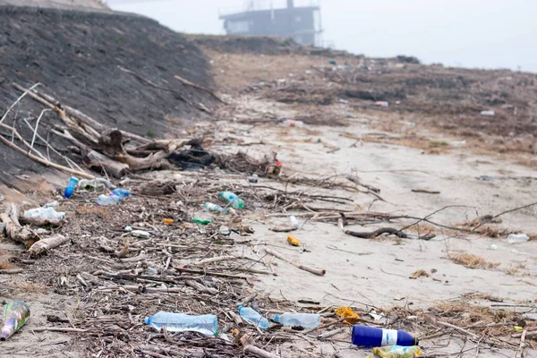 Empty used dirty plastic bottles left on the beach. Single use plastic as a human addiction that is destroying our planet. Ecology concept.