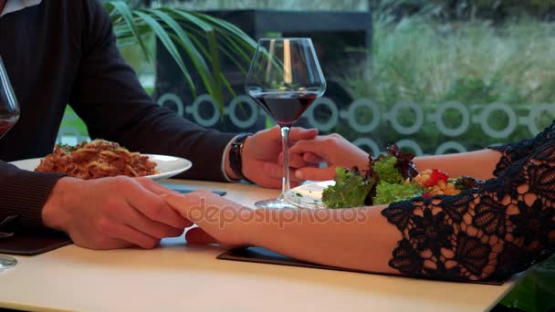 Mãos masculinas e femininas conectadas através de uma mesa com refeição e vinho — Vídeo de Stock