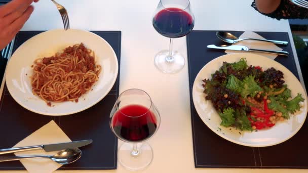 Um homem e uma mulher comem refeição à mesa com vinho — Vídeo de Stock