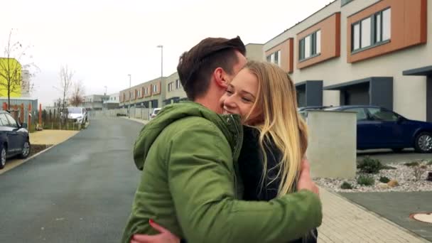 En attraktiv unga paret hälsar varandra med en kram på en väg i en stadsdel, leenden och skratt — Stockvideo