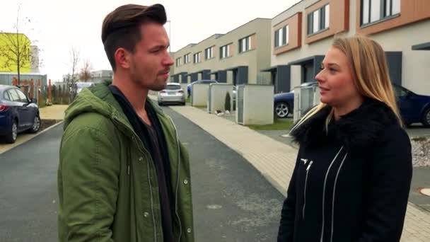 A man and a woman greet each other shaking hands on a road in a neighborhood, a man points at and talks about something off the camera — Stock Video