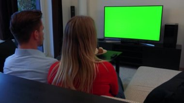 Genç bir çift yeşil bir ekran rahat bir oturma odasında Tv izliyor