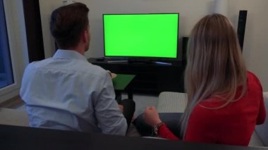 Birkaç (ermesinin başlarını kameraya) üzerinde alkış ve rahat bir oturma odasında yeşil bir ekran bir Tv izler, sonra kutluyor
