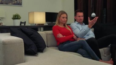 Oturma odasında bir kanepede oturuyor ve kamera kapalı bir şey hakkında çileden bir genç, çekici çift