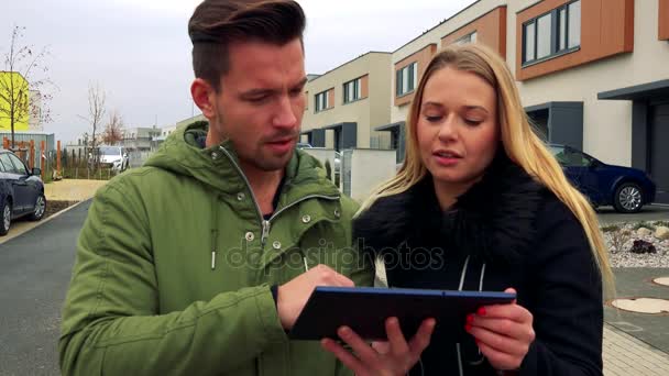 Чоловік і жінка обговорюють щось про планшет, який він тримає на порожній вулиці — стокове відео