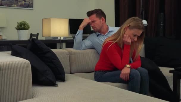 Mladá, atraktivní pár sedí a přemýšlí nešťastně na gauči — Stock video