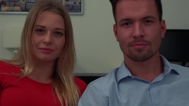 Um homem e uma mulher, jovens e atraentes, sorriem para a câmera - close-up — Vídeo de Stock