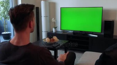 Bir adam çığlık atıyor ve öfkeyle yeşil bir ekran bir Tv, gesticulates