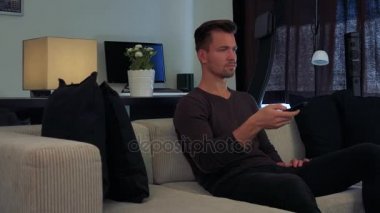 Genç ve yakışıklı bir adam kamera kapalı olan bir Tv, bir denetleyici Puan