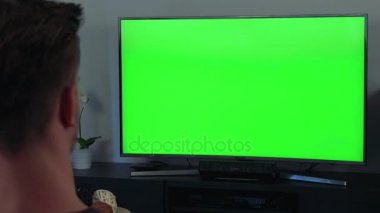 Bir adam, kafasının arkasına kameraya, yeşil bir ekran bir Tv izliyor