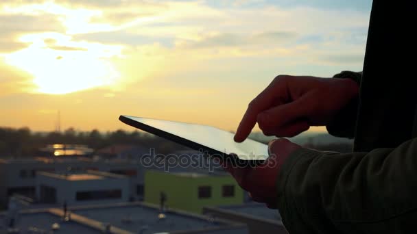 Las manos trabajan en una tableta, puesta de sol en el fondo — Vídeos de Stock