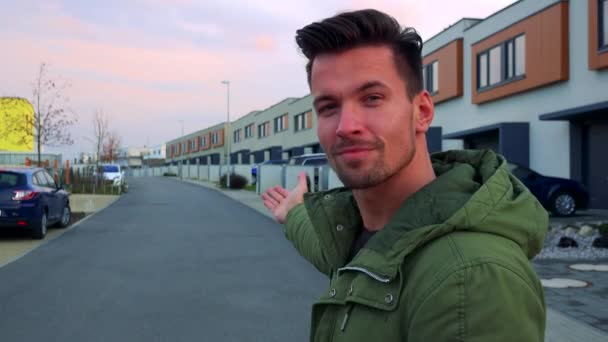 Een jonge, knappe man nodigt u met gebaren van zijn handen te kijken naar de straat achter hem — Stockvideo