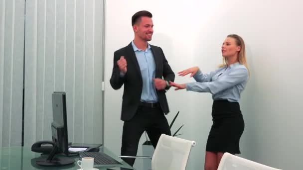 Un hombre y una mujer (jóvenes y atractivos) bailan en una oficina — Vídeos de Stock