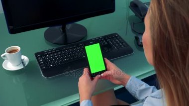 Bir kadın bir akıllı telefon ile yeşil bir ekran görünüyor.